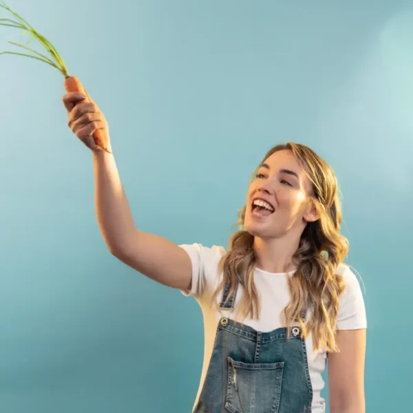 Femme récoltant des carottes dans un terreau bio surélevé.